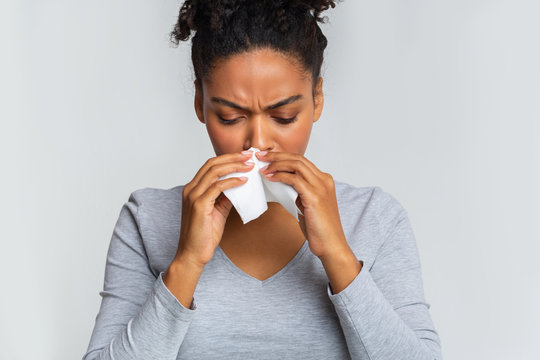 Woman touching her nose with napkin, having runny nose