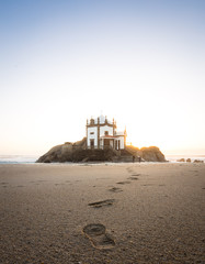 Chapel Senhor da Pedra sitting on the rock formation surrounded by ocean