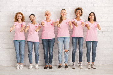 Obraz premium Happy Women In Awareness T-Shirts Gesturing Thumbs-Up Over White Wall