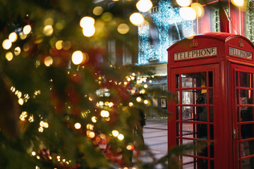 Christmas time in London: a red telephone booth in front of an illuminated Christmas Tree in Central London, UK, during night time - Powered by Adobe