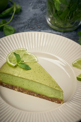 Slice of raw green cheesecake with lime and mint, decorated slice of lime. Healthy organic summer dessert pie.