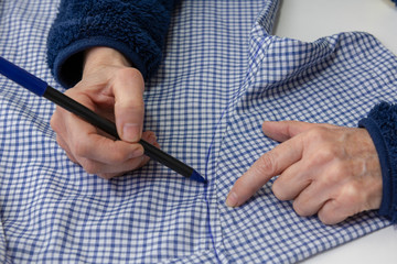 La mano de la costurera marcando una tela antes de cortar
