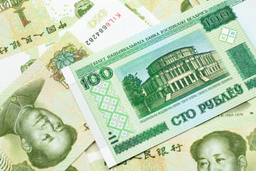 A green hundred ruble bank note from Belarus on a bed of Chinese one yuan bank notes close up in macro