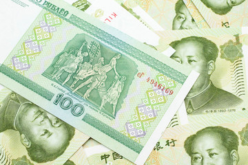 A green hundred ruble bank note from Belarus on a bed of Chinese one yuan bank notes close up in macro