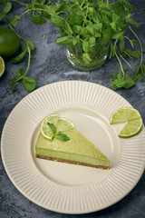 Slice of raw green cheesecake with lime and mint, decorated slice of lime. Healthy organic summer dessert pie.