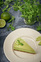 Slice of raw green cheesecake with lime and mint, decorated slice of lime. Healthy organic summer dessert pie.