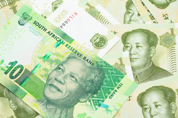 A close up image of a green ten rand bank note from South Africa in macro on a bed of Chinese one yuan bank notes