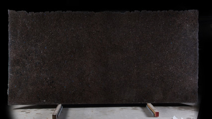 A large slab of natural stone of brown color with shiny blue sparkles called granite Labrador Antique