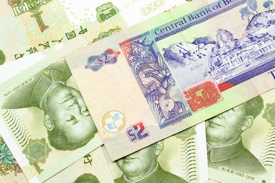 A close up image of a colorful two dollar bill from Belize with a pile of Chinese one yuan bank notes in macro