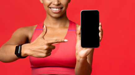 Sporty girl pointing at mobile phone blank screen