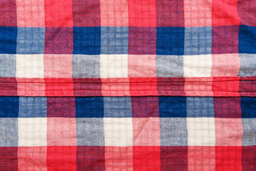 Plaid material texture. Red, blue and white cage clothes background