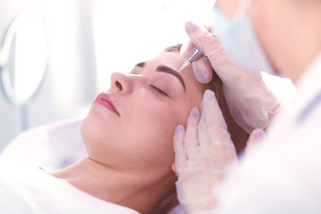A young girl having red lips permanent makeup, micropigmentation