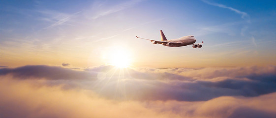 Naklejka na ściany i meble Commercial airplane flying over dramatic sunset