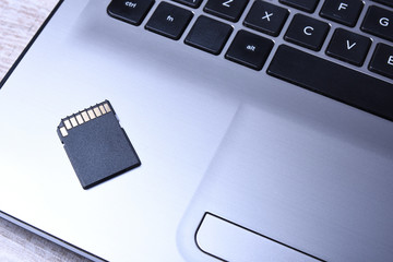 Micro SD memory card adapter on grey laptop keyboard on the wooden table. close up