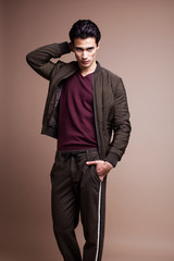 Obraz premium young pretty asian man posing in fashion style on light brown background, lifestyle people concept