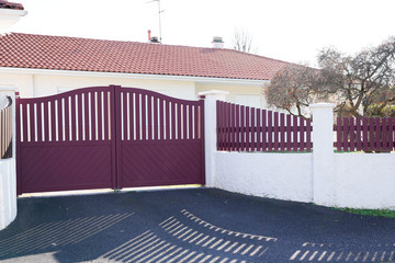 red metal driveway entrance gates set in modern new house