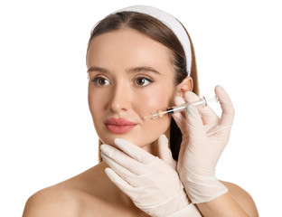 Young woman receiving filler injection against white background