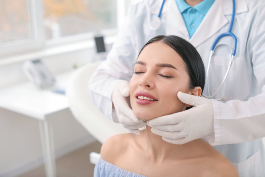 Plastic surgeon examining young woman's face prior to operation in clinic