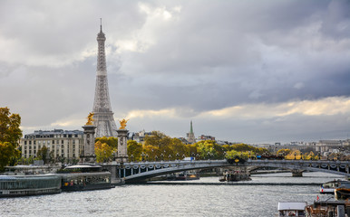 Bunte Herbstansicht der Seine in Paris, Frankreich, mit dem Pont Alexandre III und dem Eiffelturm im Hintergrund mit dem dramatischen blauen Himmel