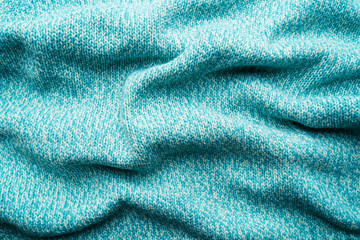 Fototapeta na wymiar Crumpled texture of a blue turquoise knitted fabric. Sweater background