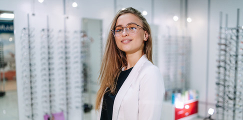 optician is standing with many glasses in background in optical shop. Stand with spectacles....