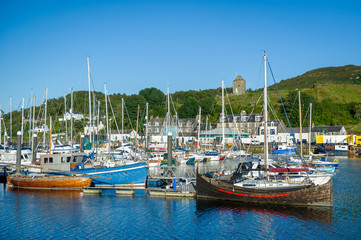 Fototapeta na wymiar Old wooden boas and modern sailing yachts at Tarbert marina. Hebrides sailing cruise, Scotland.