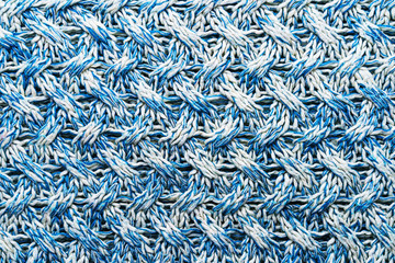 Blue and white texture of a knitted woolen fabric with a patterned weave. Sweater background