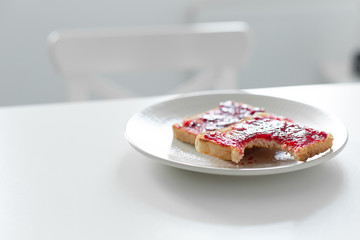 Bitten toast with jam on the table. Late for work did not have time to eat breakfast