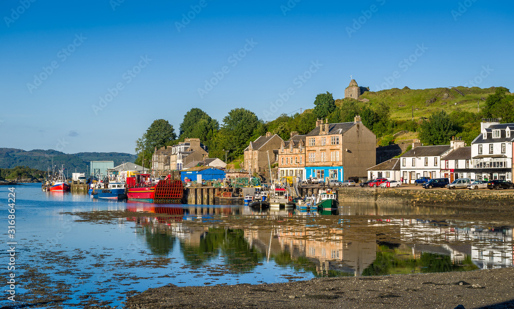 Wall mural tarbert pier with fisherman's boats and ferry. low tide water and evening light. scotland.