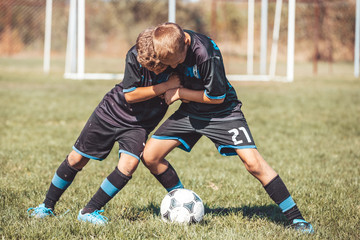 Obraz premium Boys kicking football on the sports field