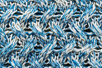 Blue and white texture of a knitted woolen fabric with a patterned weave. Sweater background