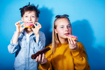 happy family brother and sister eating donuts on blue background, lifestyle people concept, boy and girl eating unhealthy food