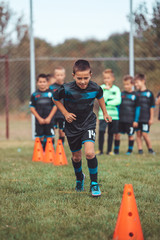 Young Footballer is running between cones and ring ladder marker