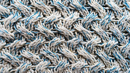 Blue and white texture of a knitted woolen fabric with a patterned weave. Sweater background