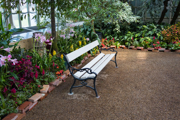 Vienna, Austria - September 3, 2019: White bench surrounded by flowers in Palmenhaus in Vienna,...