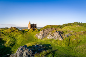 Rocky landscape and Royal Castle of Tarbert at sunset light. Terbert, Scotland.