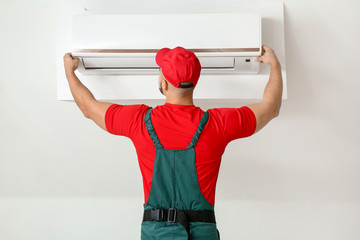 Male technician repairing air conditioner indoors