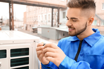 Male technician installing outdoor unit of air conditioner