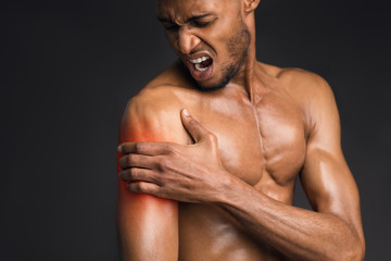 Fototapeta premium Handsome shirtless black man suffering from pain in arm