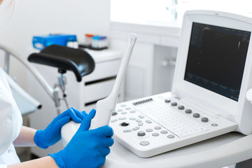 A gynecologist sets up an ultrasound machine. A transvaginal ultrasound scanner of the internal organs of the pelvis. Female health concept