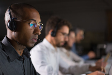 Concentrated call center operator communicating with client. African American young man in...