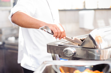 Master chief is grilling fish at open kitchen