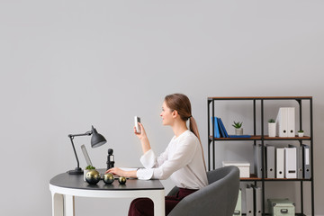 Young woman working in office with operating air conditioner