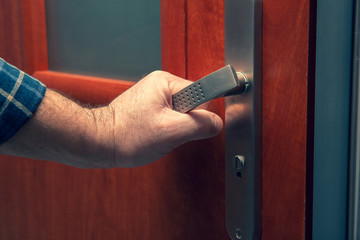 Opening or closing the door. A man holds a door handle from the door, opens or closes the door.