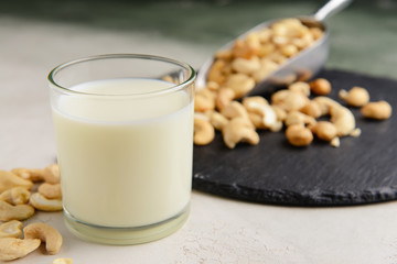 Glass of cashew milk on light background
