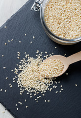 sesame seeds in a wooden spoon on a dark background