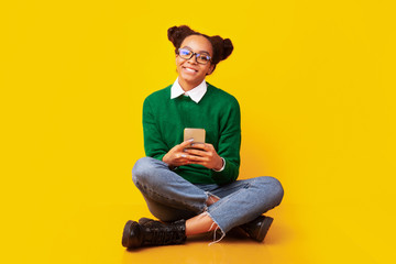 Happy black teenager sitting on floor at studio
