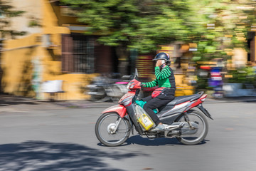 Naklejka na ściany i meble Panning motion shot of commuter in Hoi An, Vietnam.