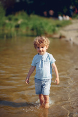 Beautiful little boy in a blue shirt. Childred playing in a summer beach. On a sand