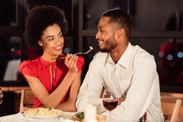 Attractive Black Woman Feeding Boyfriend During Dinner In Fancy Restaurant